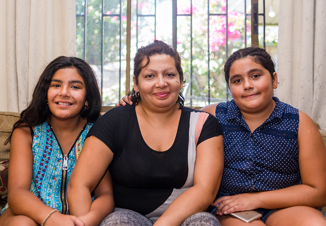 Madre sentada con sus dos hijas al lado.