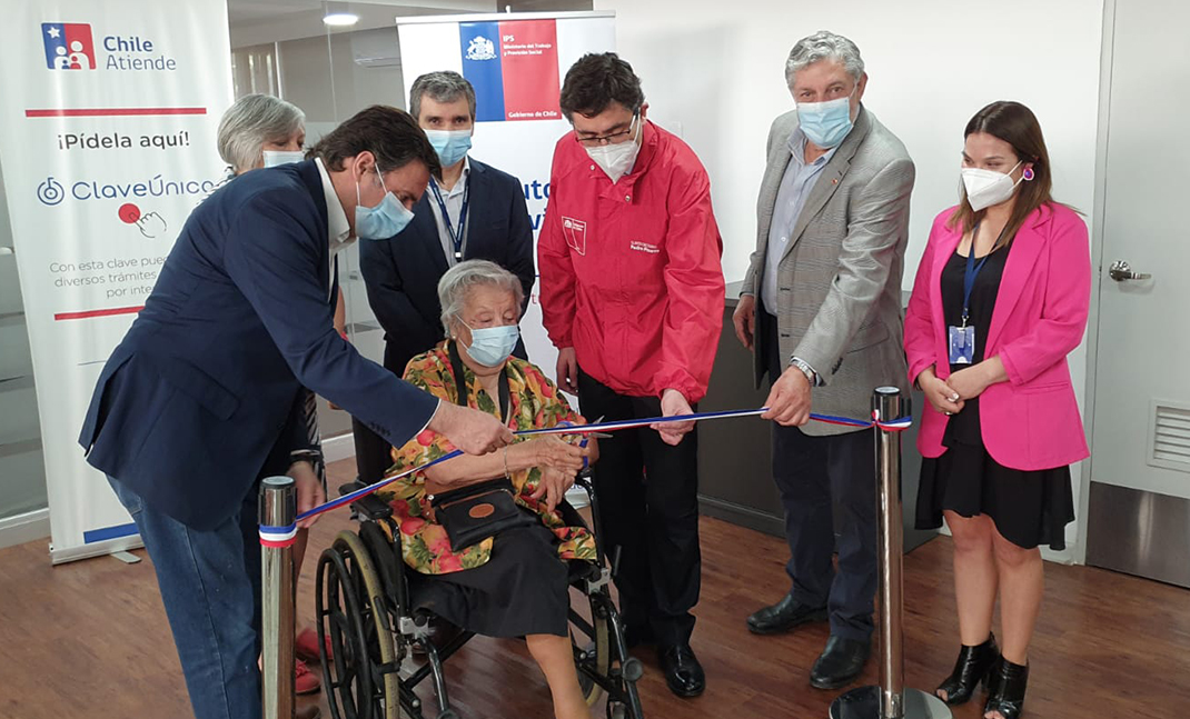 Autoridades de Gobierno, junto a usuaria en silla de ruedas, en corte de cinta inauguración sucursal.
