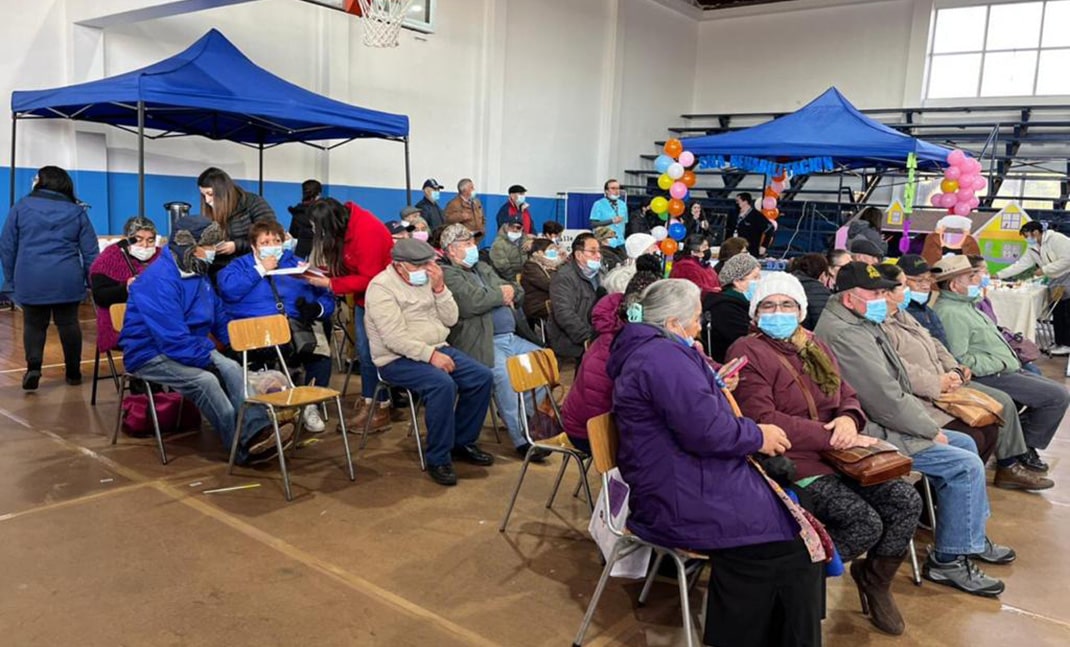Adultos mayores reunidos en un gimnasio, sentados.